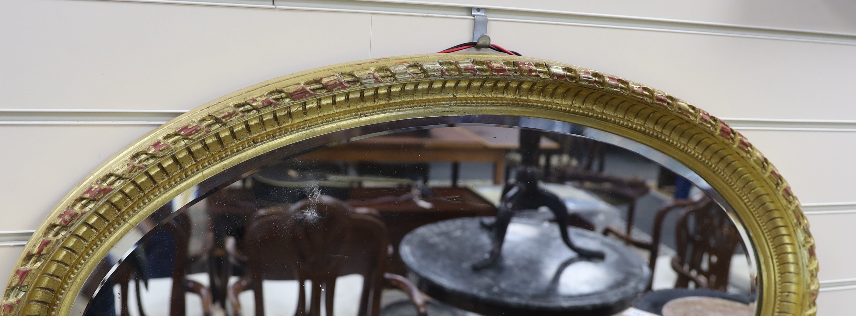 An oval moulded gilt wall mirror width 86cm, height 56cm.